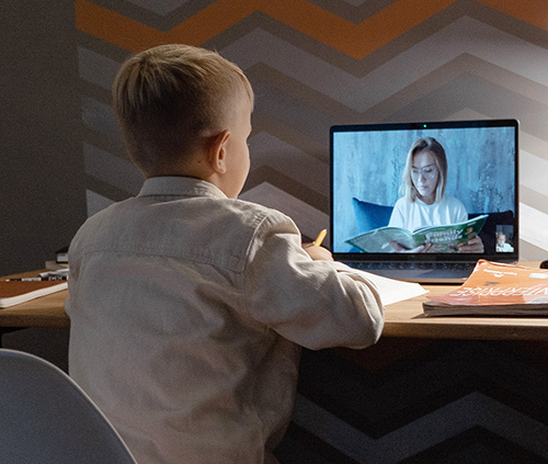 Elementary school student attending an online class with his laptop